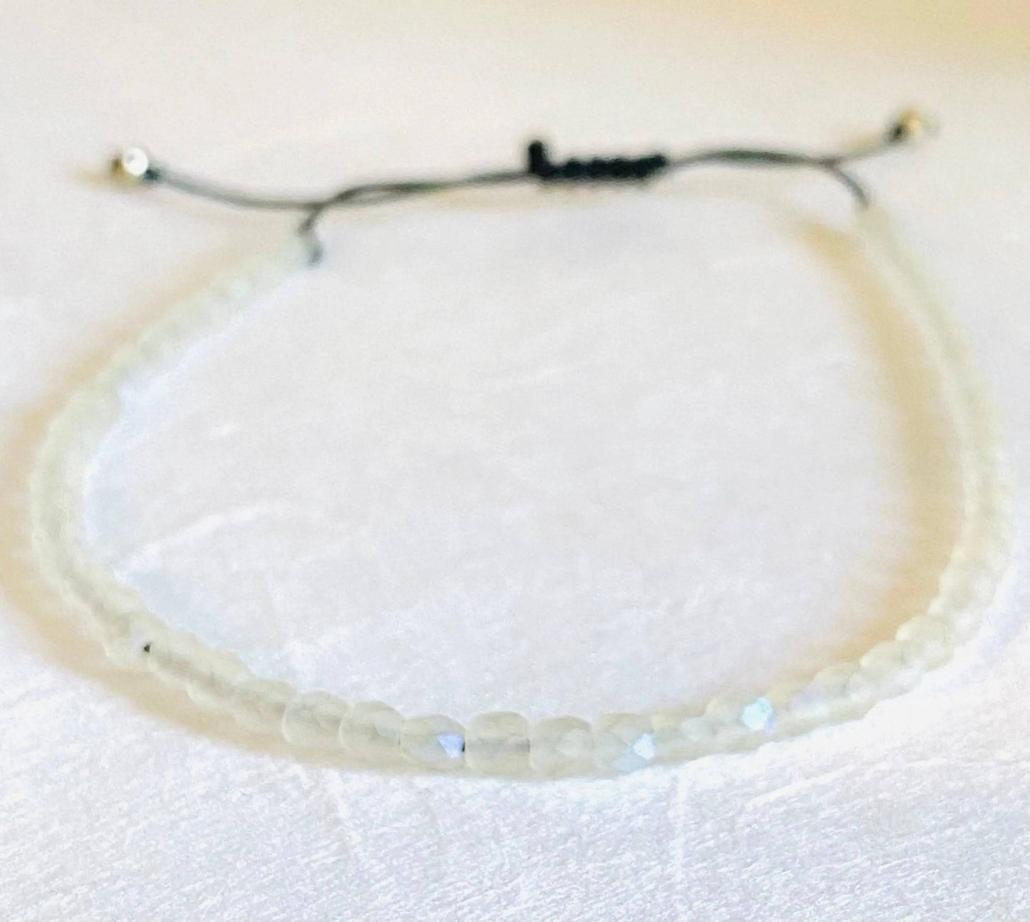 Clear iridescent glass bead adjustable bracelet with black cord. Elegant and stackable, great for birthday gifts or personal style.