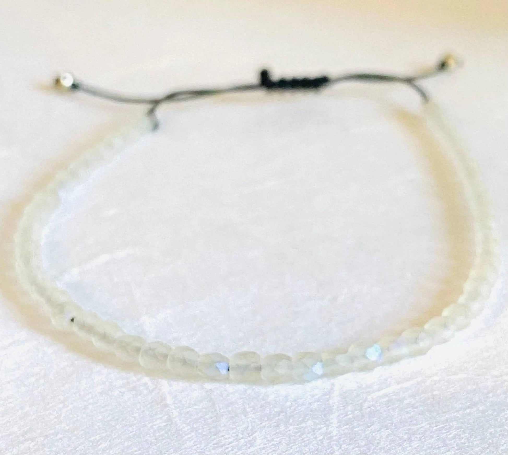 Clear iridescent glass bead adjustable bracelet with black cord. Elegant and stackable, great for birthday gifts or personal style.