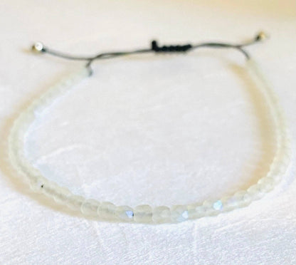 Clear iridescent glass bead adjustable bracelet with black cord. Elegant and stackable, great for birthday gifts or personal style.