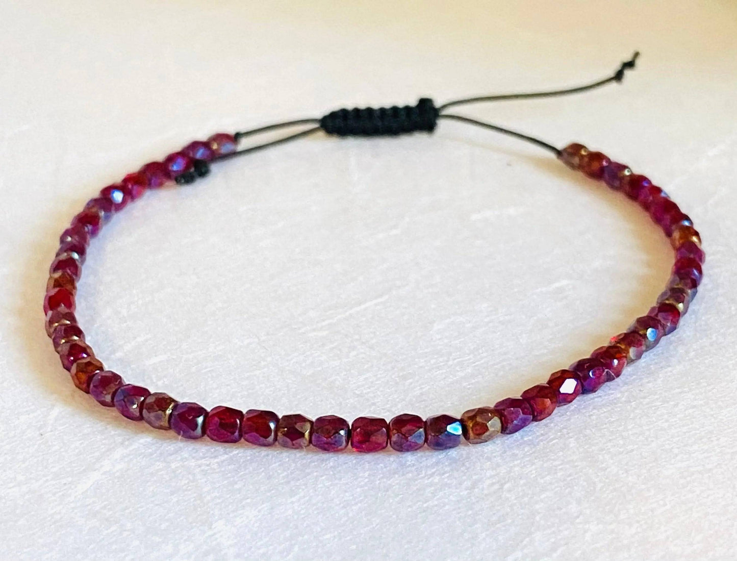 Red and purple faceted glass bead adjustable bracelet with black cord. Stackable friendship bracelet ideal for gifting or layering.