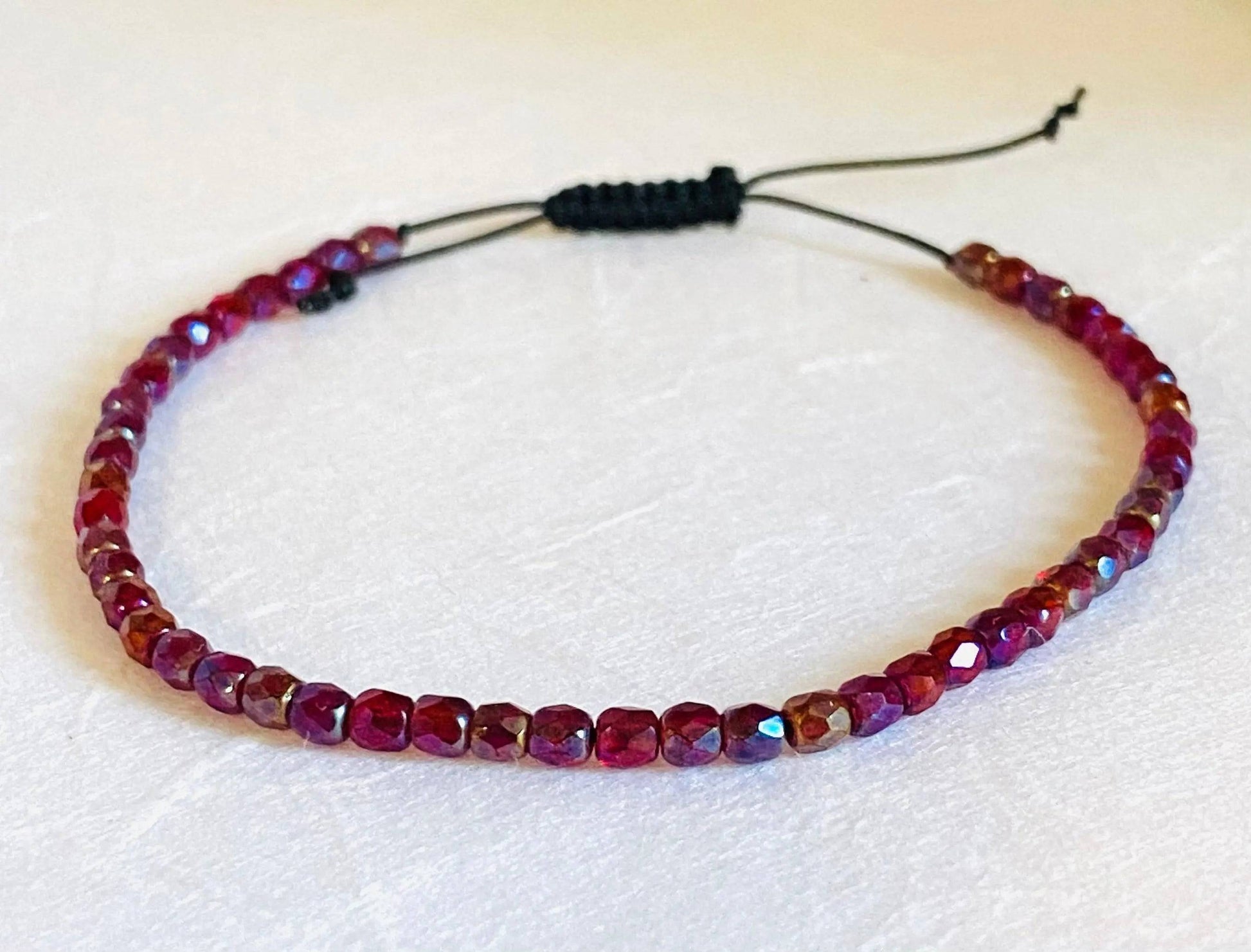 Red and purple faceted glass bead adjustable bracelet with black cord. Stackable friendship bracelet ideal for gifting or layering.