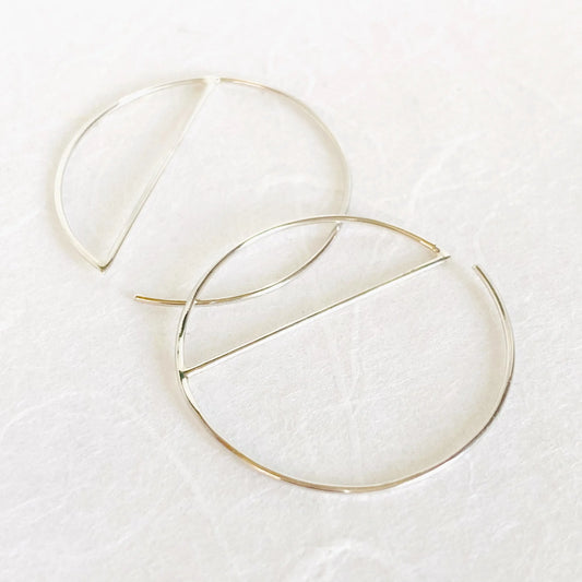 Modern silver hoops in sterling silver with minimalist half-circle bar design. 1” diameter hoop earrings crafted from 21 gauge wire.
