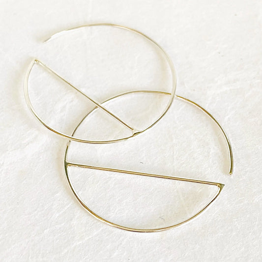 Sterling silver hoop earrings featuring a modern geometric design with a horizontal bar. Elegant 1” diameter hoops for everyday wear.