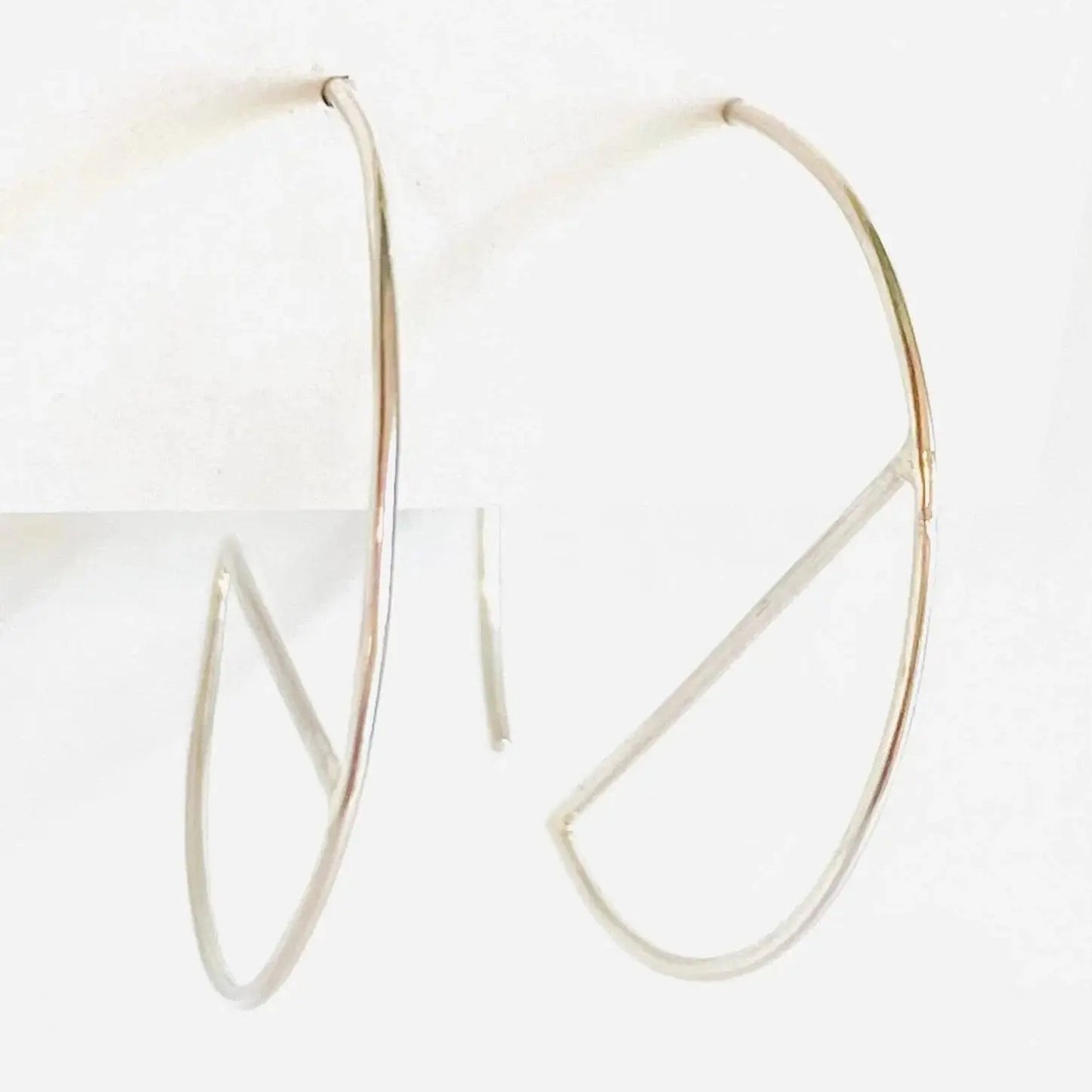 Contemporary sterling silver hoops with sleek bar accent, shown from side angle. 1” diameter earrings made from 21 gauge silver wire.