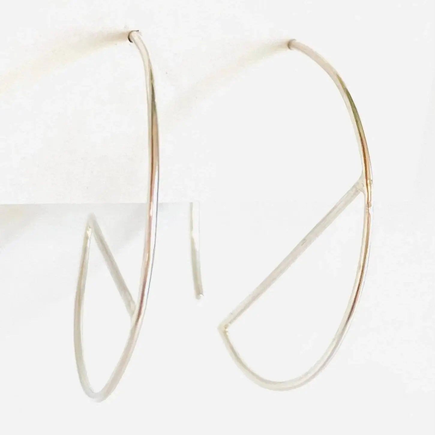 Contemporary sterling silver hoops with sleek bar accent, shown from side angle. 1” diameter earrings made from 21 gauge silver wire.
