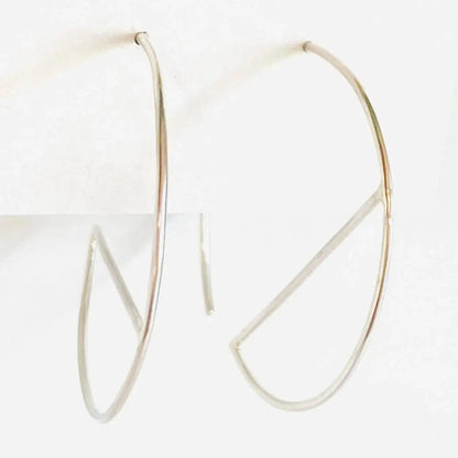 Contemporary sterling silver hoops with sleek bar accent, shown from side angle. 1” diameter earrings made from 21 gauge silver wire.