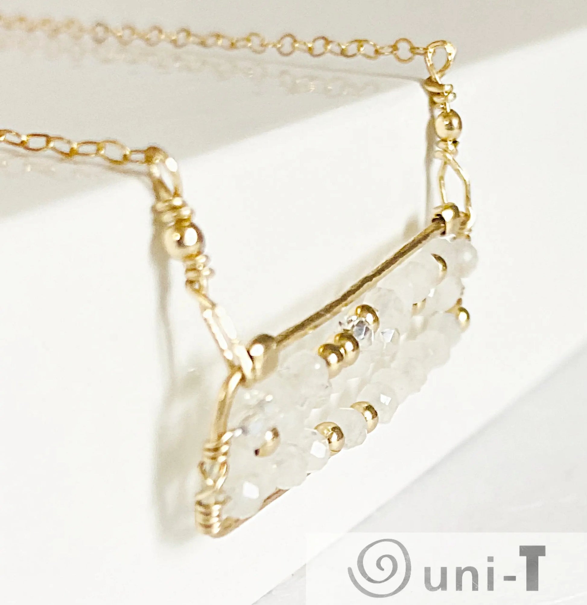 Close-up of Moonstone Bar Necklace with gold-filled wire and shimmering moonstone beads. Unique handcrafted accessory with quartz bead accents.
