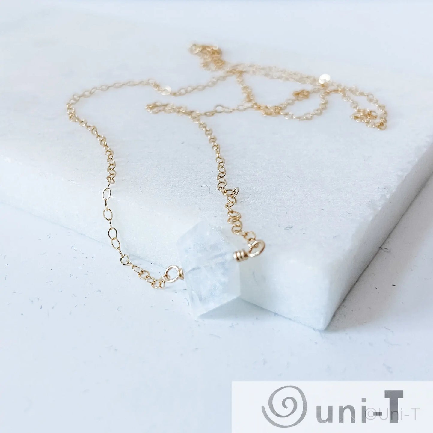 Dainty moonstone gemstone necklace laid on white marble, featuring gold-filled chain and genuine moonstone pendant for spiritual growth.