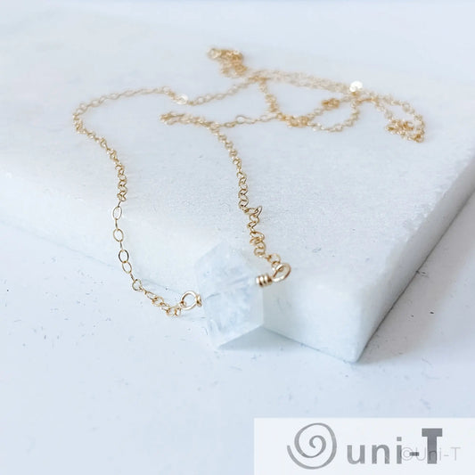 Dainty moonstone gemstone necklace laid on white marble, featuring gold-filled chain and genuine moonstone pendant for spiritual growth.