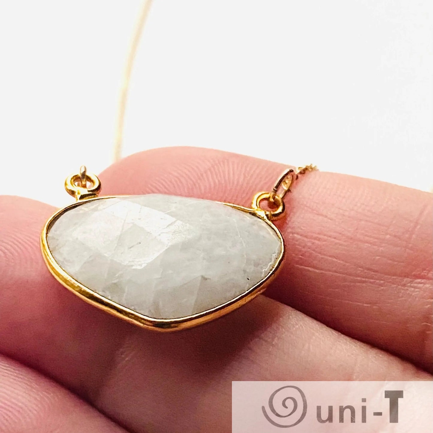 Hand holding a moonstone necklace with gold filled chain and bezel setting. Showcases the natural gemstone's clarity and craftsmanship.