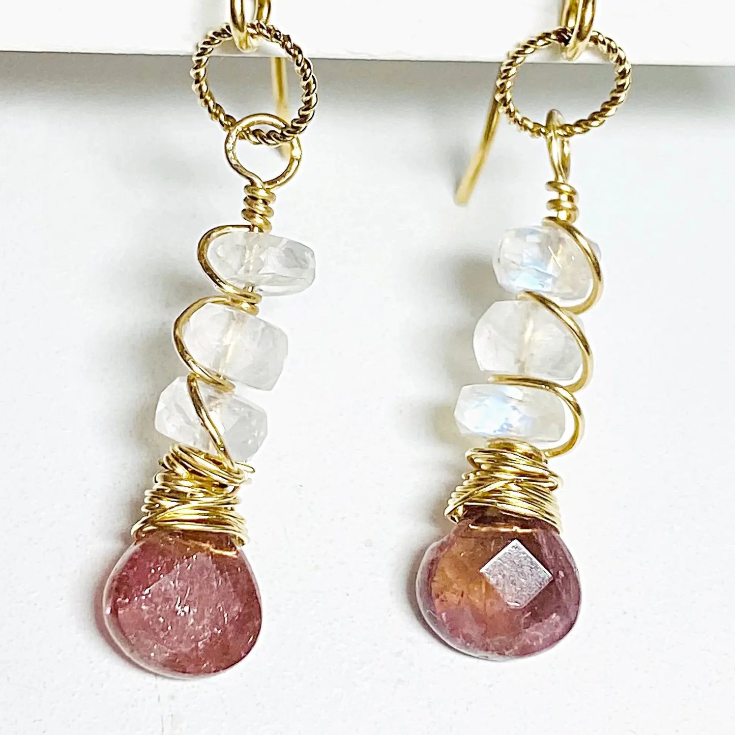 Close-up of moonstone and tourmaline earrings wrapped in gold-filled wire. Handcrafted 1.5-inch gemstone earrings with unique artisan detail.