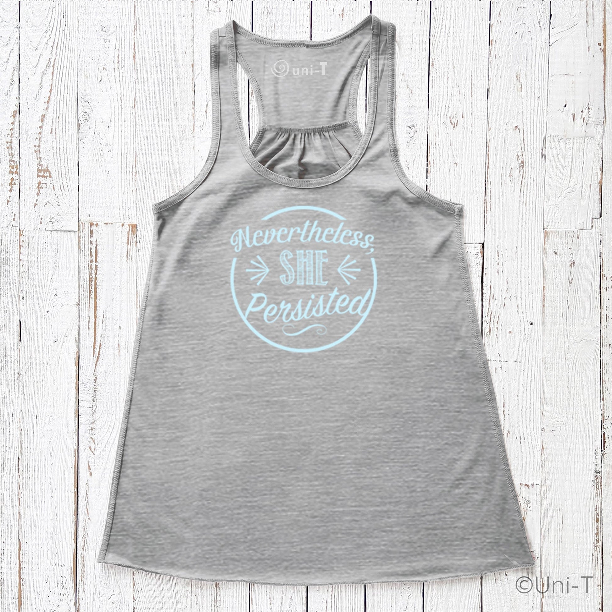 Gray racerback tank top with light blue 'Nevertheless She Persisted' print. Eco-friendly ink on strength apparel for women.