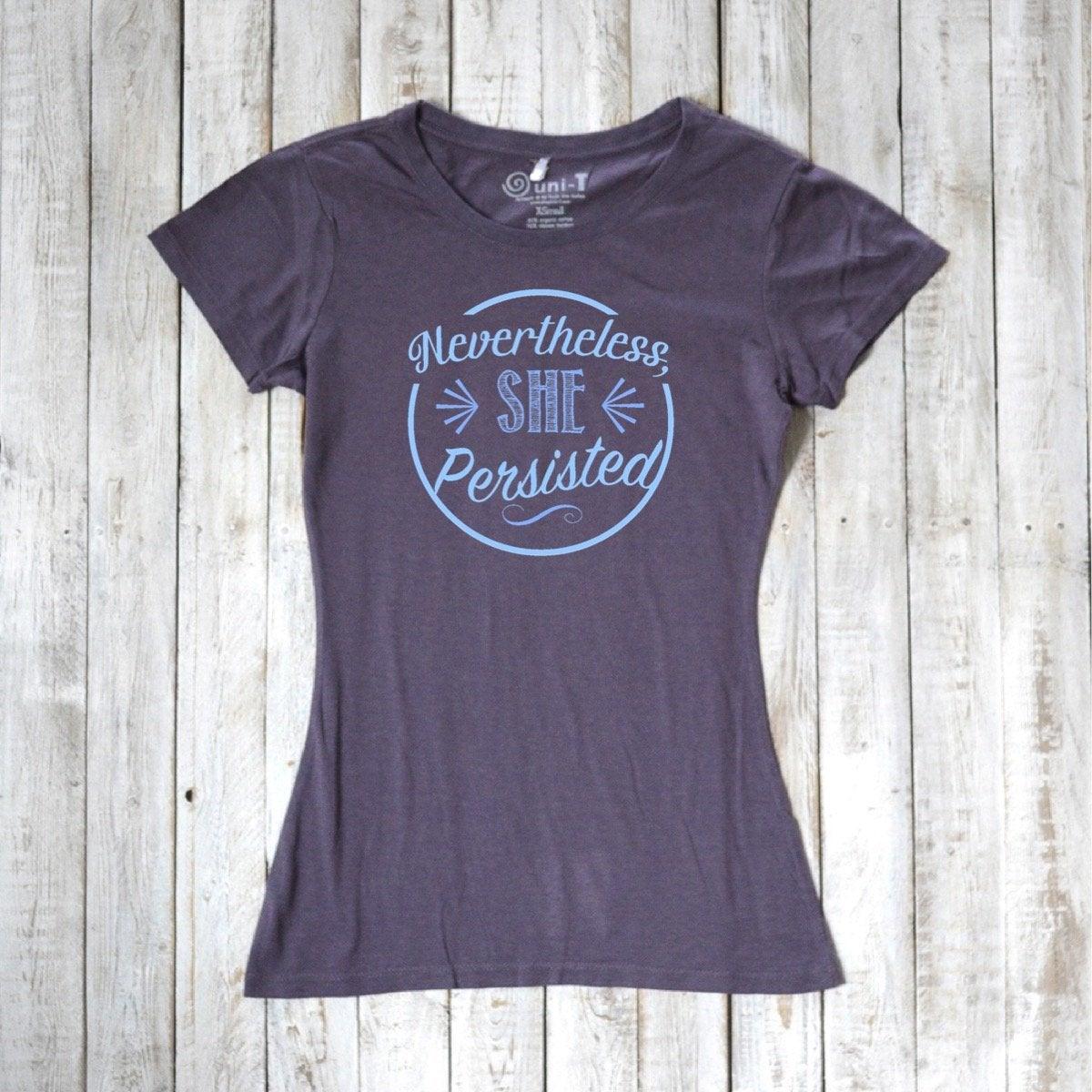 Women's 'Nevertheless She Persisted' tee in dark gray with blue text, made from bamboo and organic cotton. Feminist empowerment top by Uni-T.