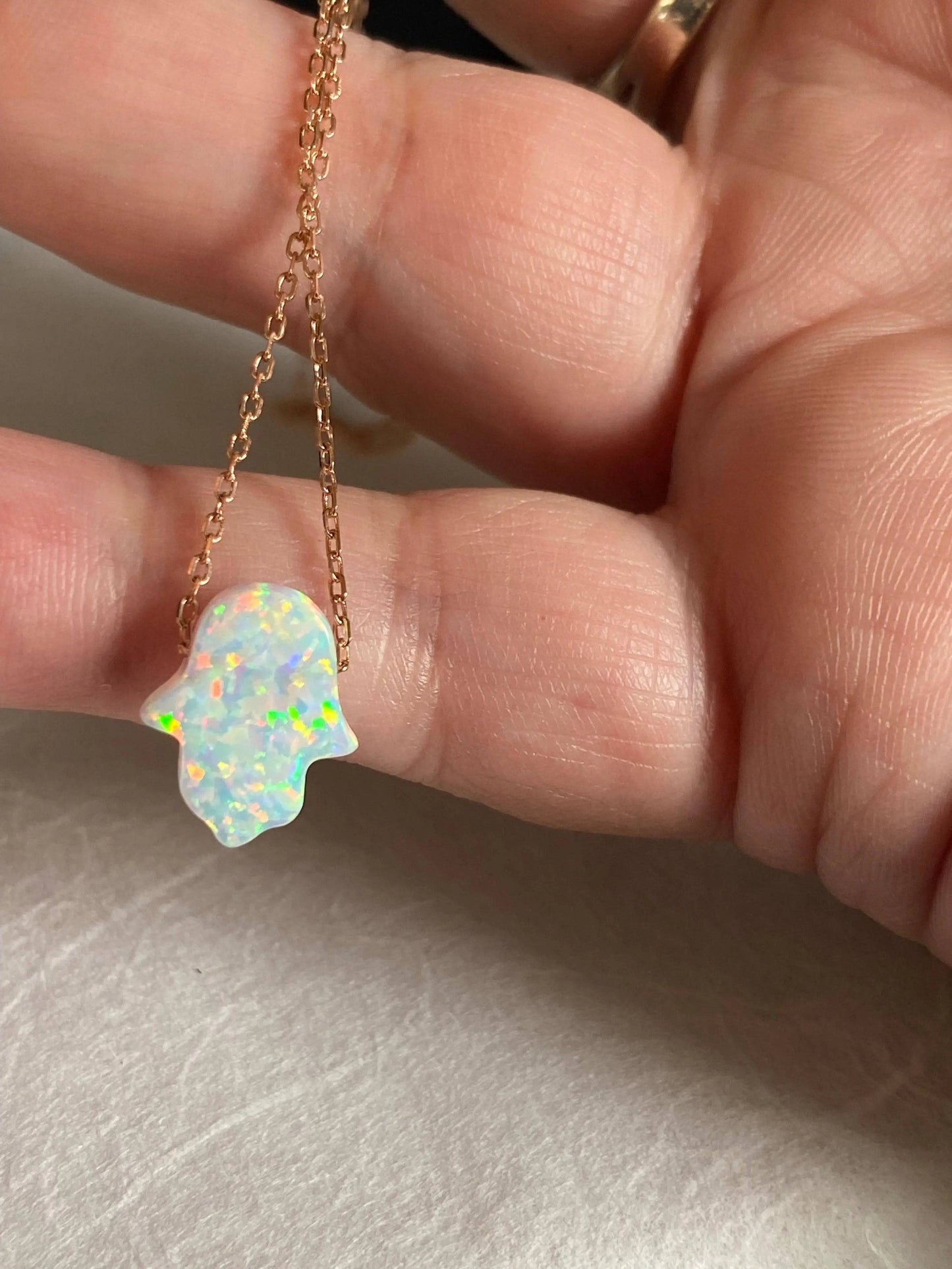 Close-up of Opal October Birthstone Necklace showing iridescent Hamsa charm on rose gold chain, perfect for everyday wear or gifting.