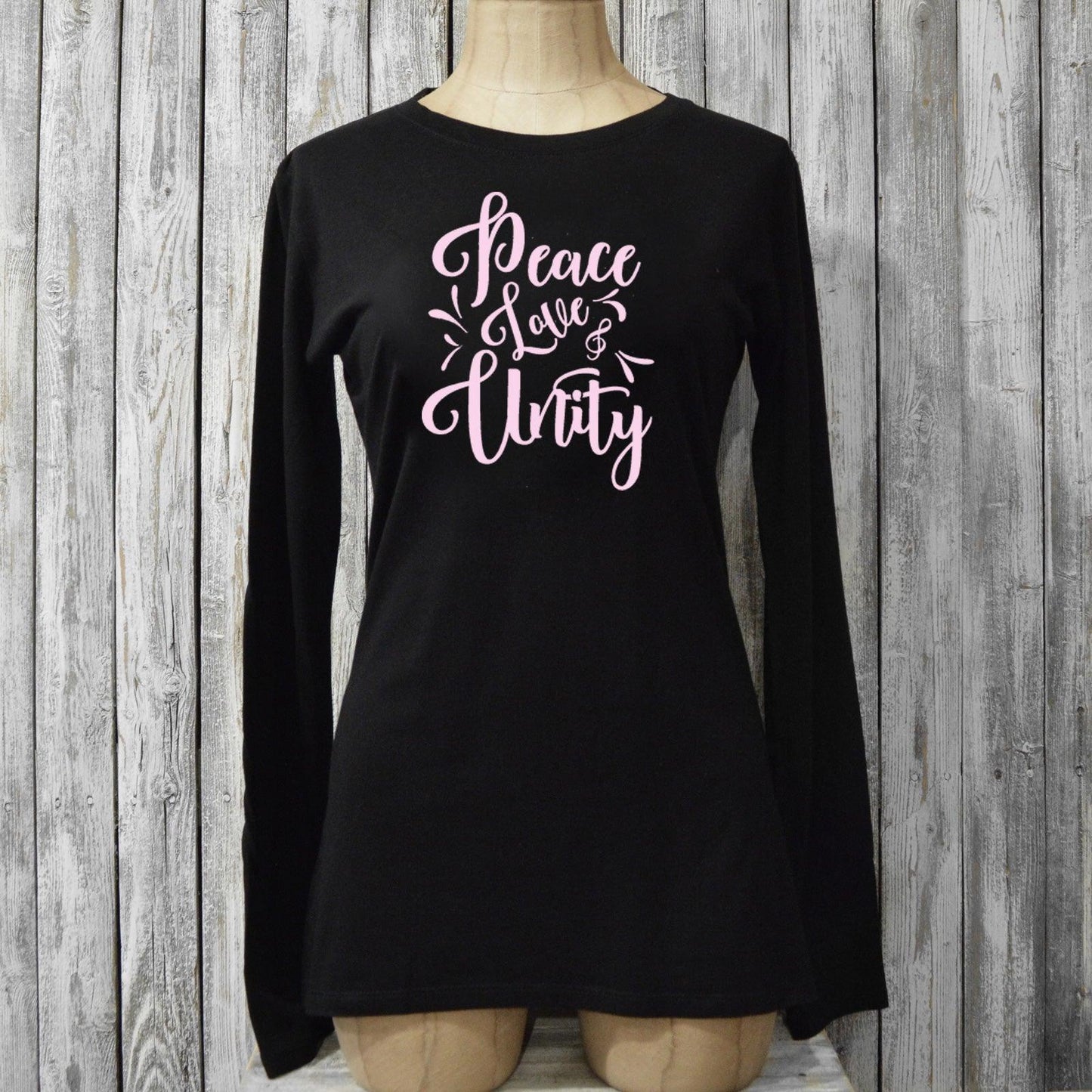 Black Women’s Peace Love & Unity Long Sleeve T-Shirt on mannequin, made from bamboo and organic cotton with pink inspirational graphic design.