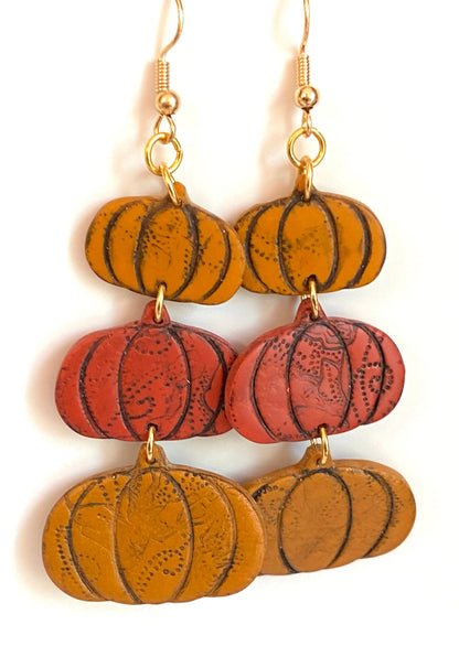 Handcrafted polymer clay pumpkin earrings in autumn tones with nickel-free gold ear wires, perfect seasonal accessory for fall outfits.