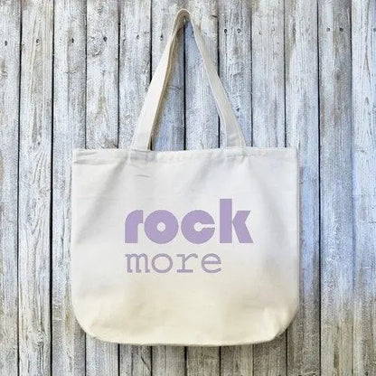 Organic canvas tote bag with 'rock more' text in bold lavender font, ideal gift for rock music lovers and eco-conscious shoppers.