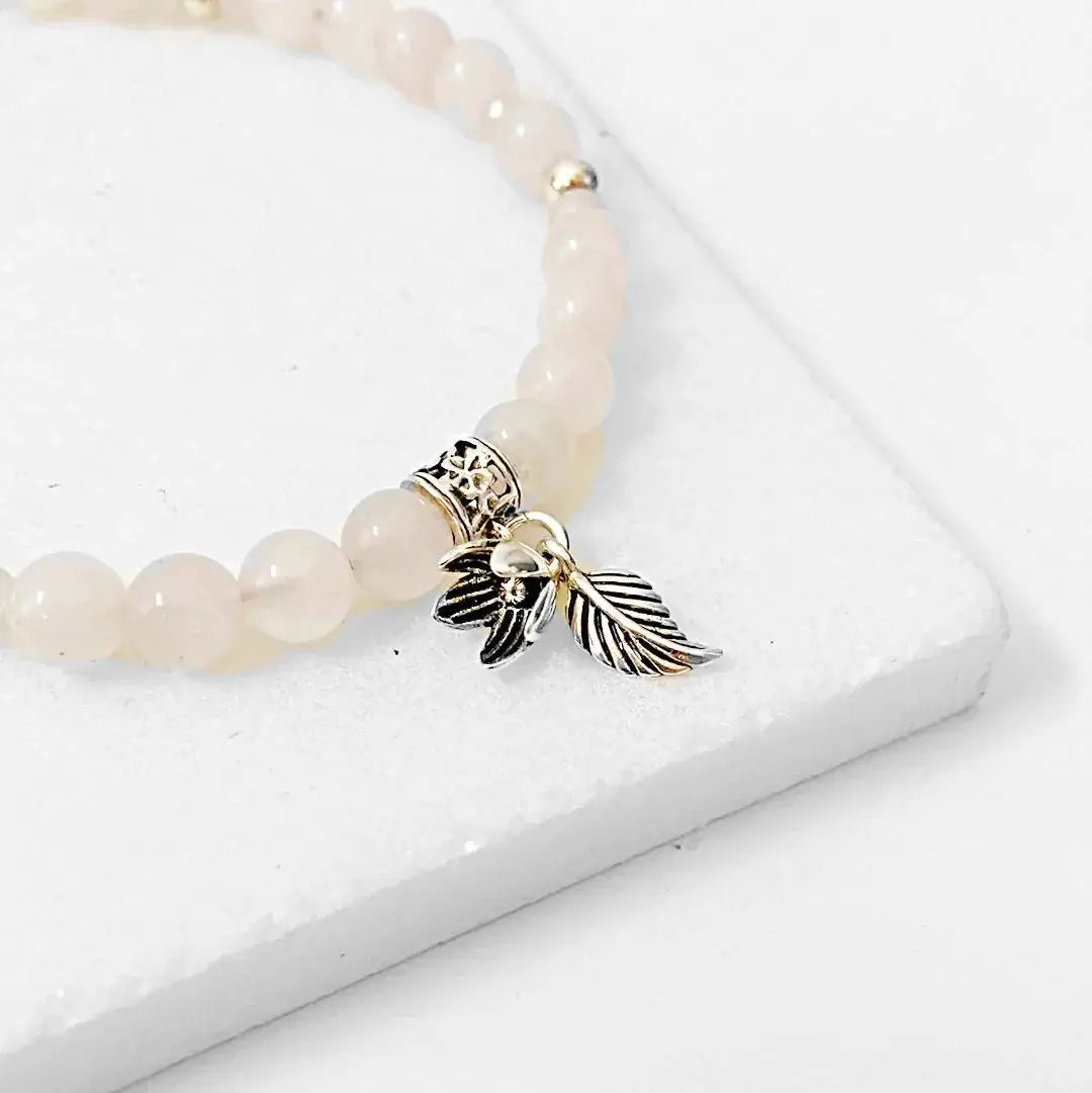 Rose Quartz Silver Flower Bracelet with sterling silver leaf and bell flower charm on round quartz beads. Elegant accessory for women.