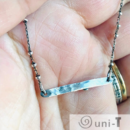 Back view of Ruby Silver Bar Necklace showing hammered silver bar and satellite chain. Handcrafted detail in modern gemstone jewelry.
