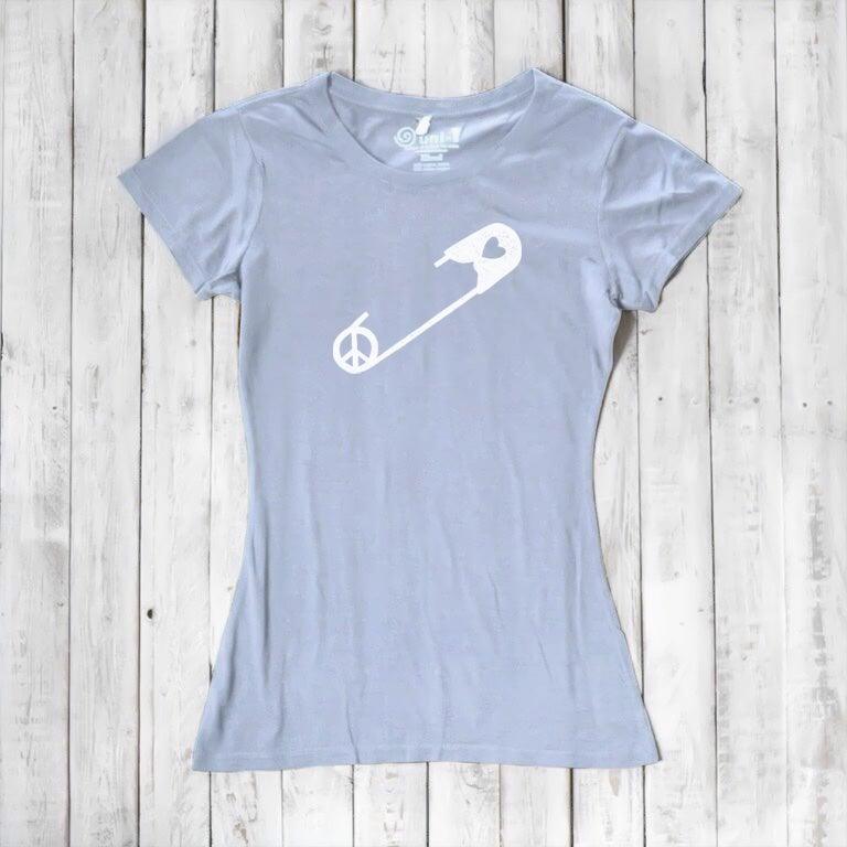 Light blue Women's Peace & Love T-Shirt with white safety pin graphic, laid flat. Eco-conscious tee promoting unity and acceptance.