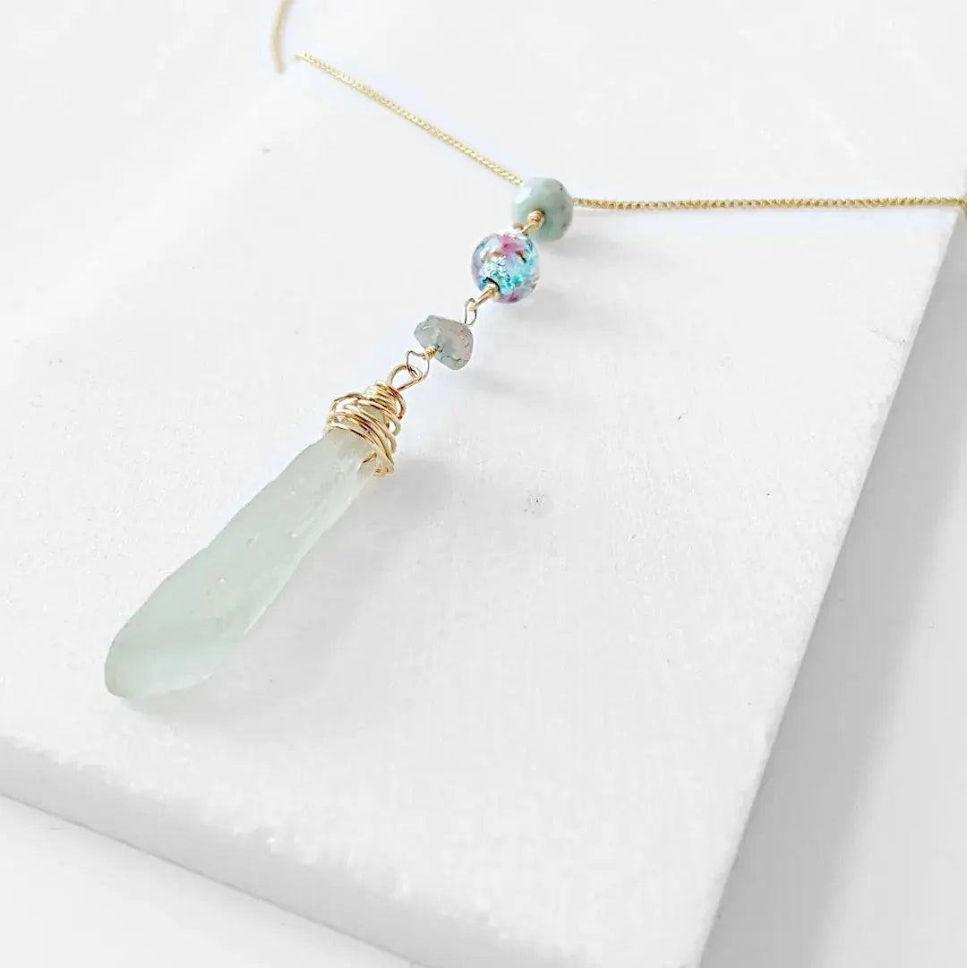 Close-up of Handmade Sea Glass Necklace featuring wire wrapped sea glass pendant, Murano floral bead, and tourmaline accents on a delicate gold chain.