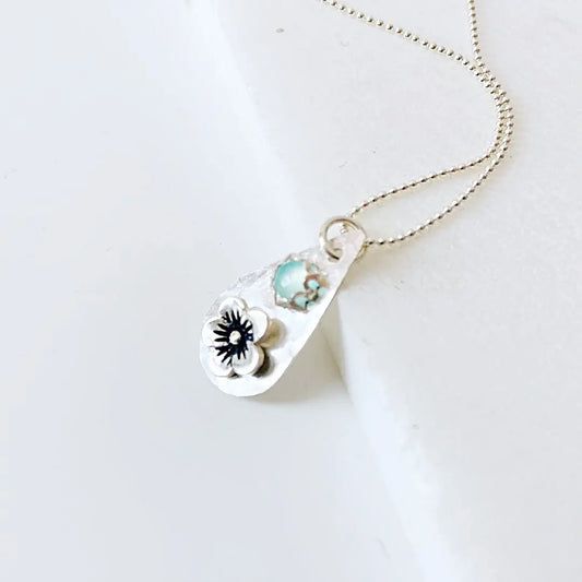 Chalcedony teardrop pendant necklace with silver flower detail, displayed on a delicate silver chain. Elegant handcrafted accessory for women.