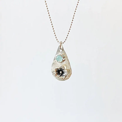 Silver flower necklace with light blue chalcedony gemstone on a ball chain. Teardrop pendant crafted in sterling silver with floral accent.