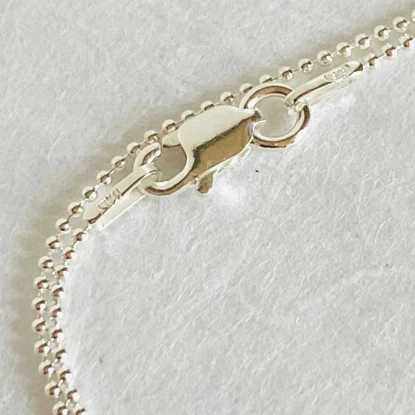 Close-up of sterling silver clasp on 1 mm beaded chain. Secure lobster clasp detail of the silver flower chalcedony necklace.
