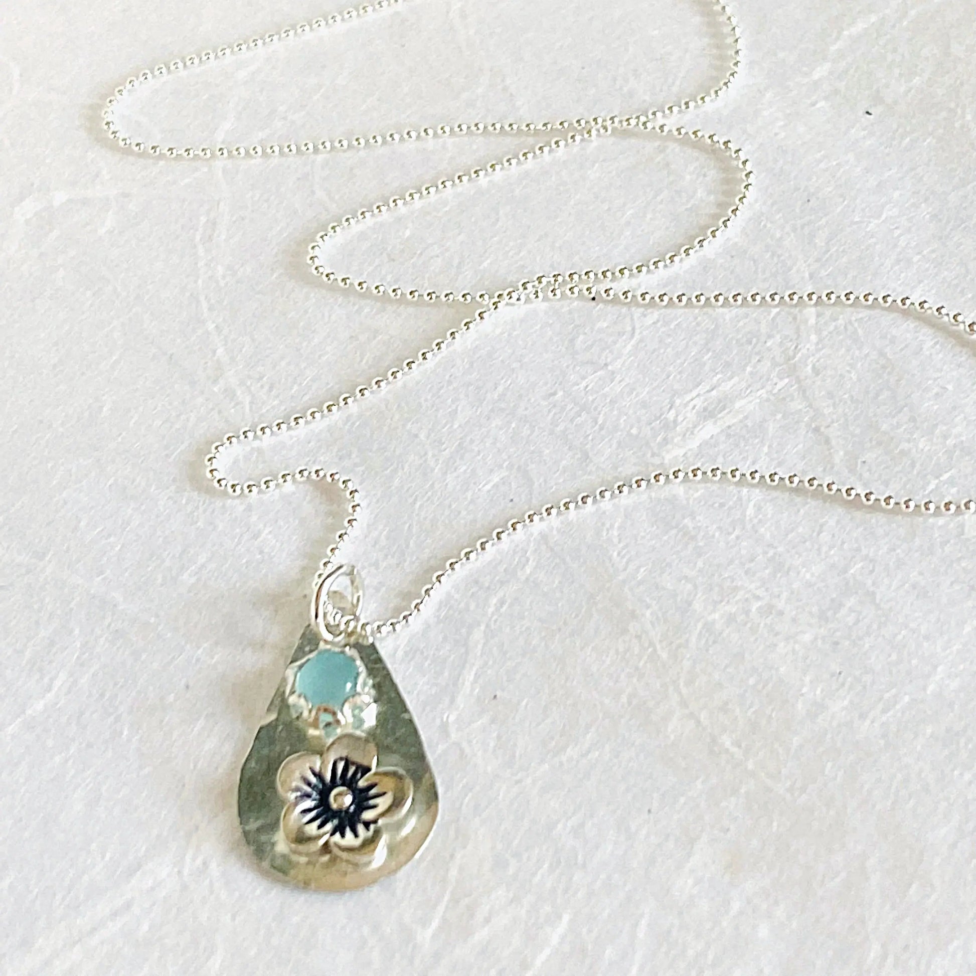 Full view of silver flower necklace with chalcedony teardrop pendant on a beaded chain. Elegant and minimalistic jewelry piece.