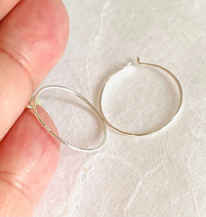 Simple sterling silver hoop earrings with 3/4” diameter shown in hand for scale. Lightweight 22 gauge hoops with secure closure for everyday wear.