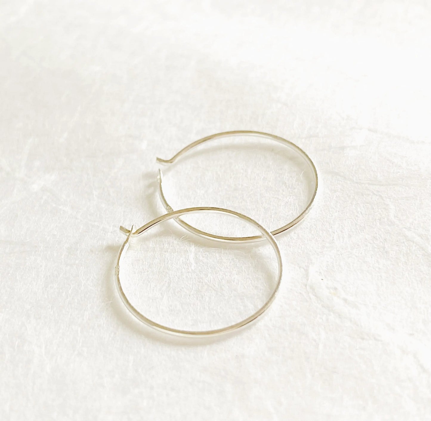 Sterling Silver Hoops - Simple Silver Hoops with 3/4” diameter and 22 gauge wire, shown on a white textured background. Classic minimalist earrings.
