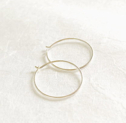 Sterling Silver Hoops - Simple Silver Hoops with 3/4” diameter and 22 gauge wire, shown on a white textured background. Classic minimalist earrings.