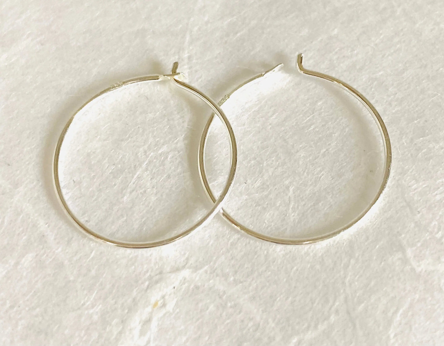 Pair of Sterling Silver Hoops - Simple Silver Hoops laid flat, showcasing their lightweight, timeless design perfect for everyday wear.