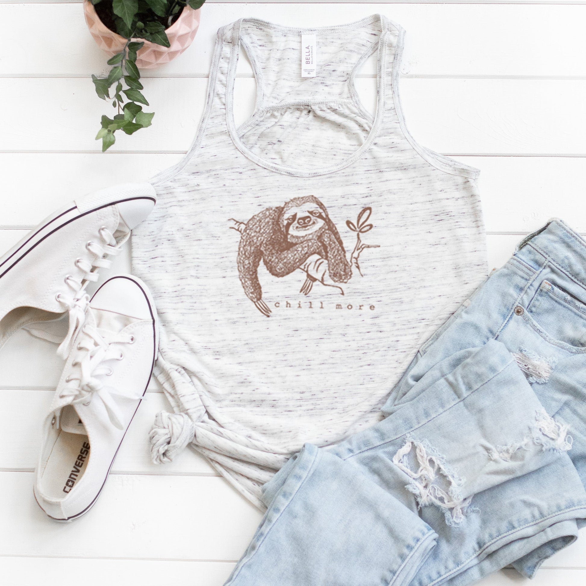 "Chill More" Women's Flowy Tank Top in heather white styled with jeans and sneakers, featuring a cute sloth print for slow living fashion.