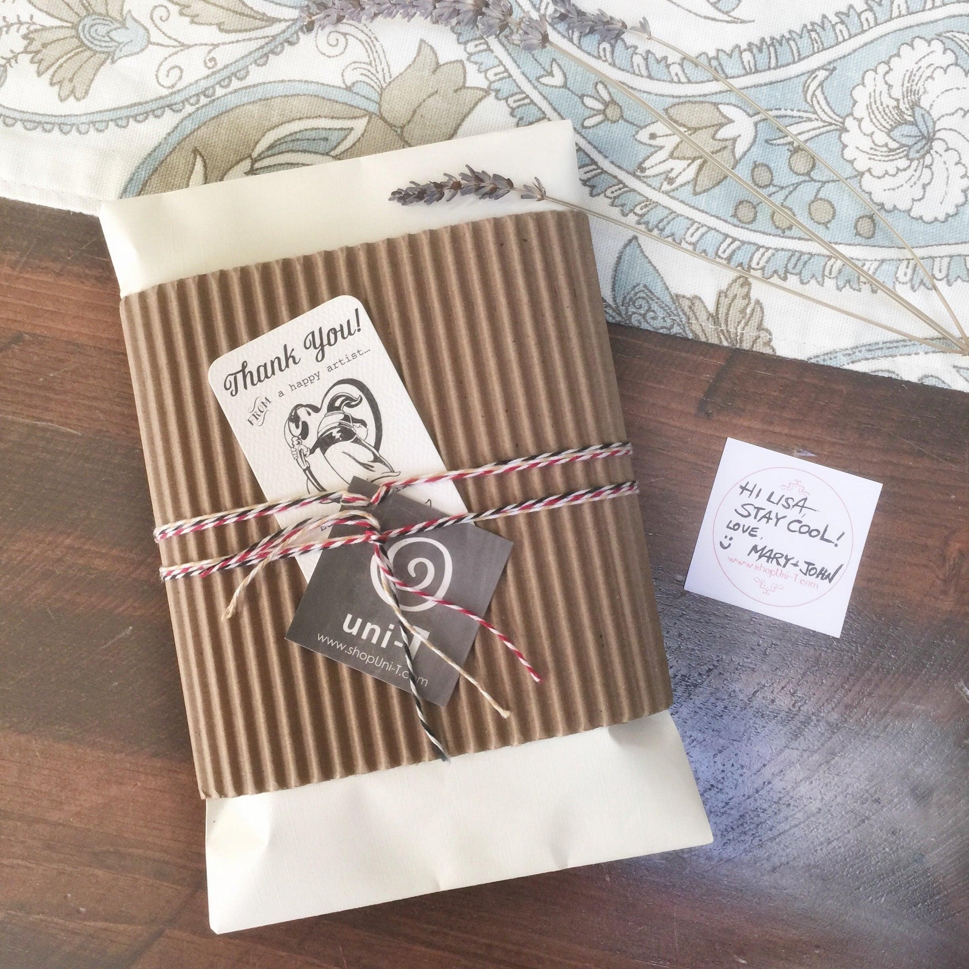 Eco-friendly Uni-T packaging with thank you note and twine-wrapped bamboo-organic cotton t-shirt, perfect for gifting sustainable apparel.