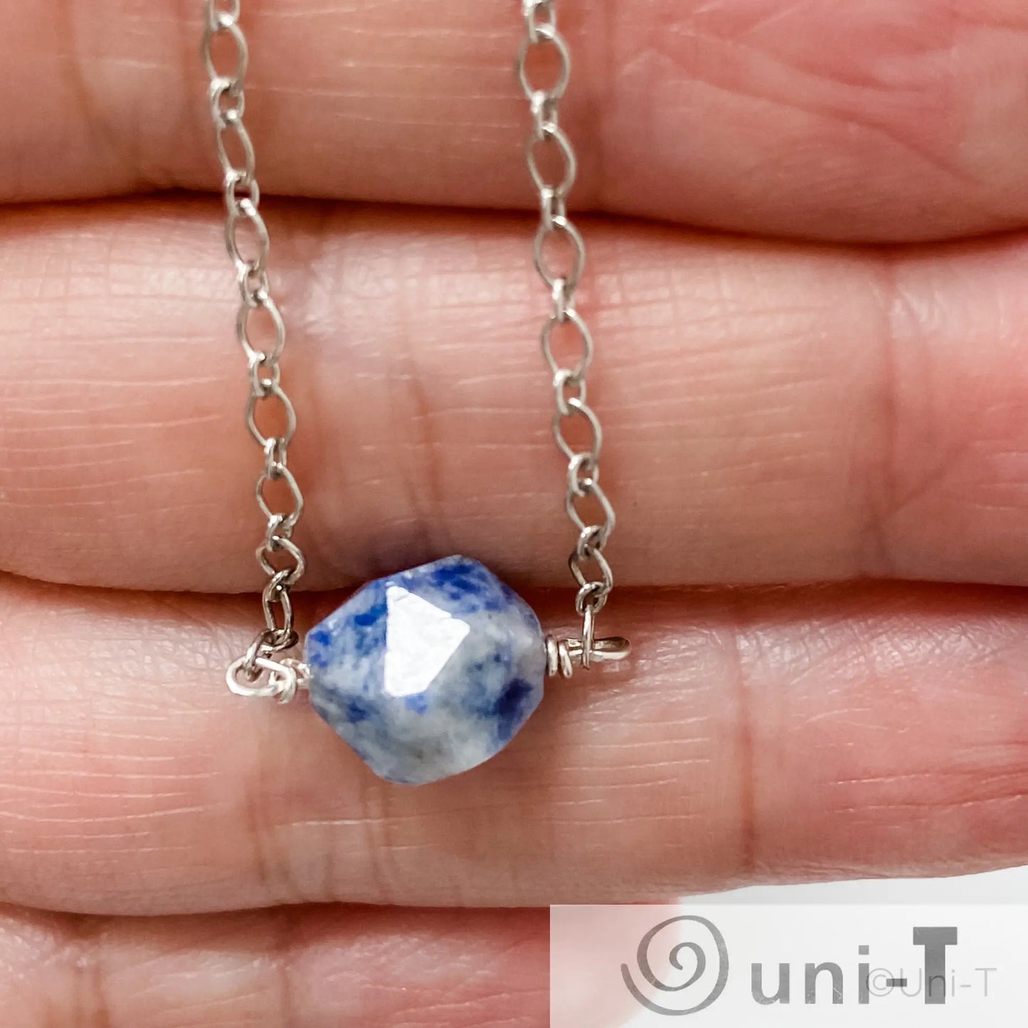 Close-up of Uni-T's Sodalite Gemstone Necklace showing the detailed cut of the blue stone and sterling silver chain links.