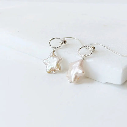 White star-shaped freshwater pearl earrings with silver wire wrapped loops. Delicate and modern jewelry for women.