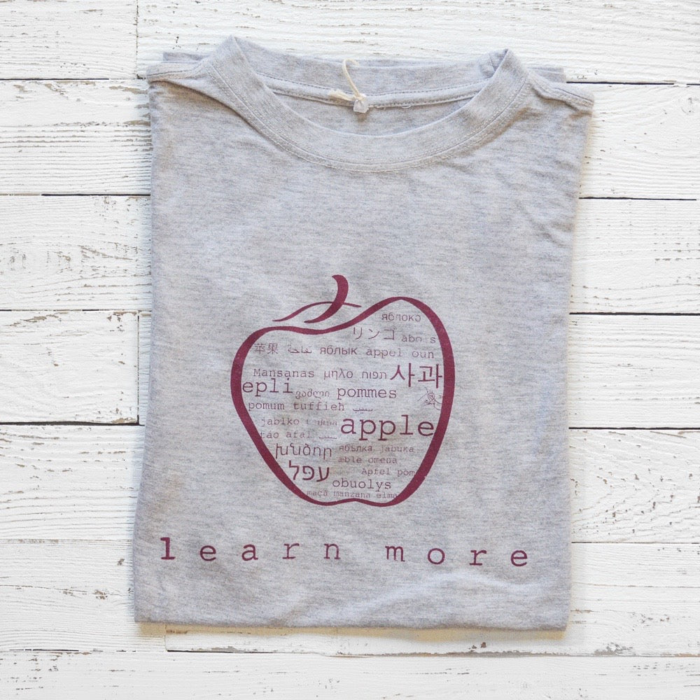 Folded grey Men's Teacher T-Shirt in Bamboo & Organic Cotton with apple graphic and 'learn more' text, ideal gift for educators.