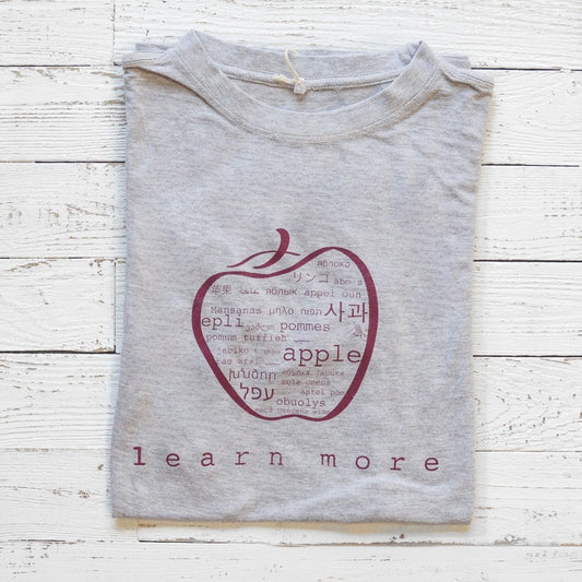 Folded grey Men's Teacher T-Shirt in Bamboo & Organic Cotton with apple graphic and 'learn more' text, ideal gift for educators.