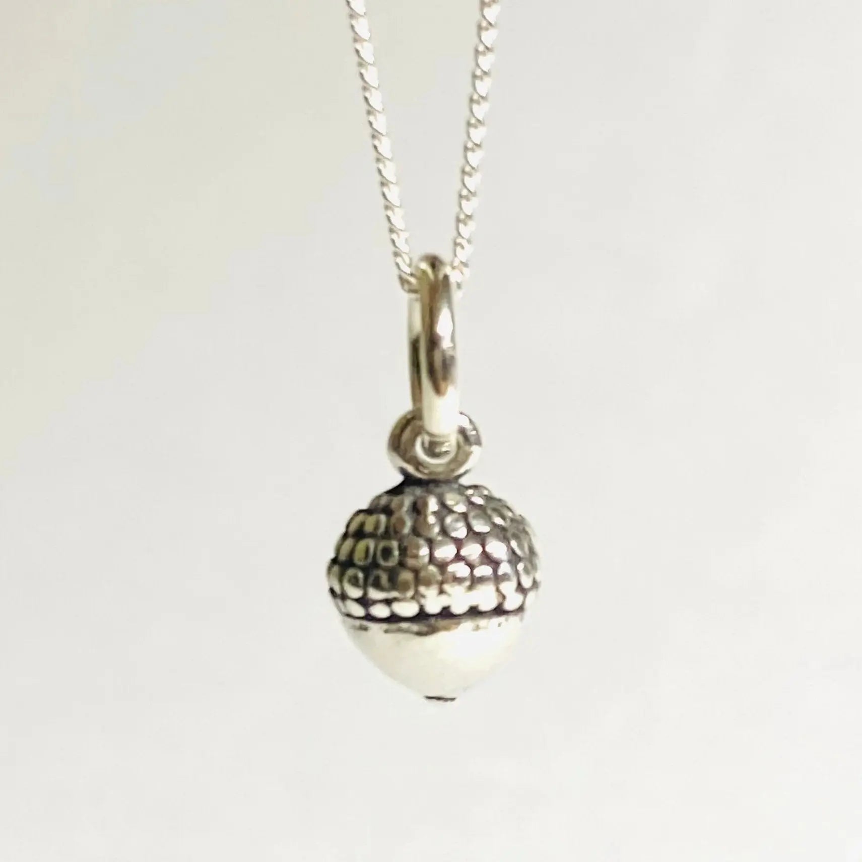 Detailed view of textured sterling silver acorn charm on a delicate 16-inch chain, part of the Tiny Acorn Charm Necklace collection.