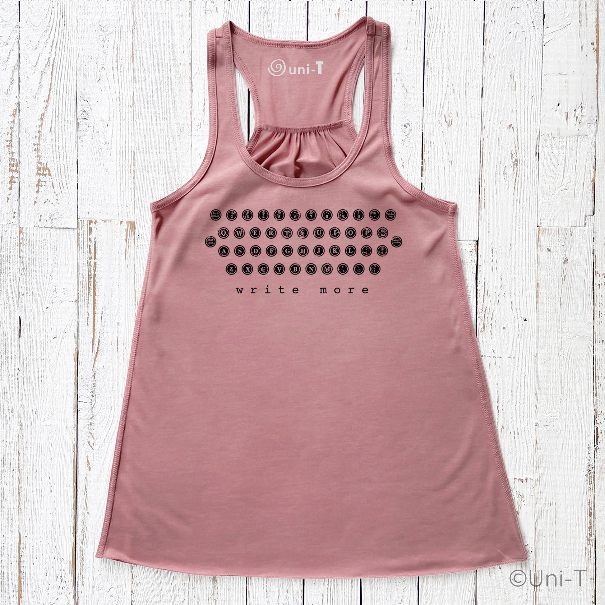 Dusty rose "Write More" tank top with vintage typewriter design. Flowy fit and soft fabric blend for creative comfort.