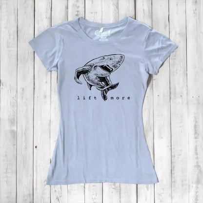 Light blue women's shark graphic T-shirt with 'Lift More' text. Sustainable bamboo and organic cotton gym motivation tee.