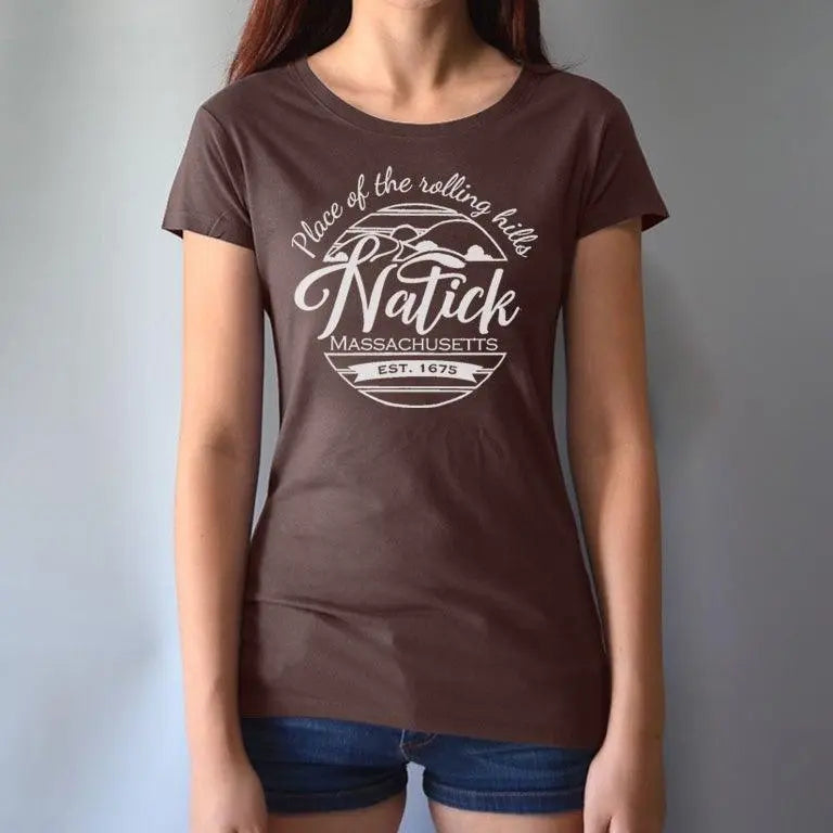 Model wearing brown women's Natick T-Shirt with 'Place of the Rolling Hills' Massachusetts graphic. Made from bamboo and organic cotton for sustainable comfort.