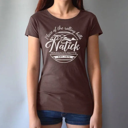 Model wearing brown women's Natick T-Shirt with 'Place of the Rolling Hills' Massachusetts graphic. Made from bamboo and organic cotton for sustainable comfort.
