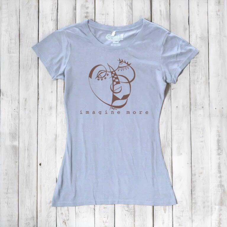 Light blue Women's Cubism Face T-Shirt in bamboo & organic cotton with brown abstract face design and 'imagine more' text. Artistic eco-friendly top.