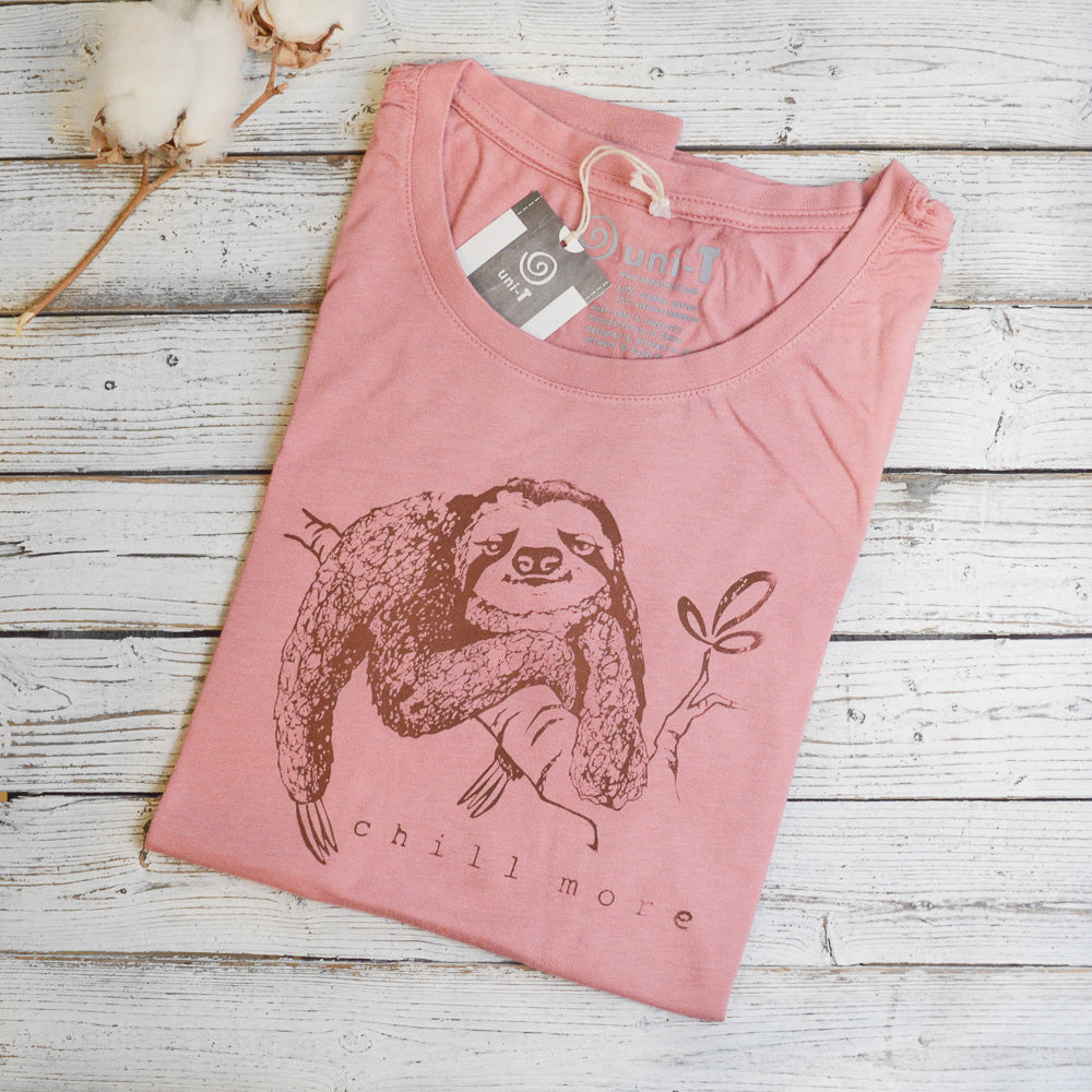 Pink folded women's sloth graphic T-shirt made from bamboo and organic cotton with 'Chill More' slogan. Soft and eco-conscious fashion.