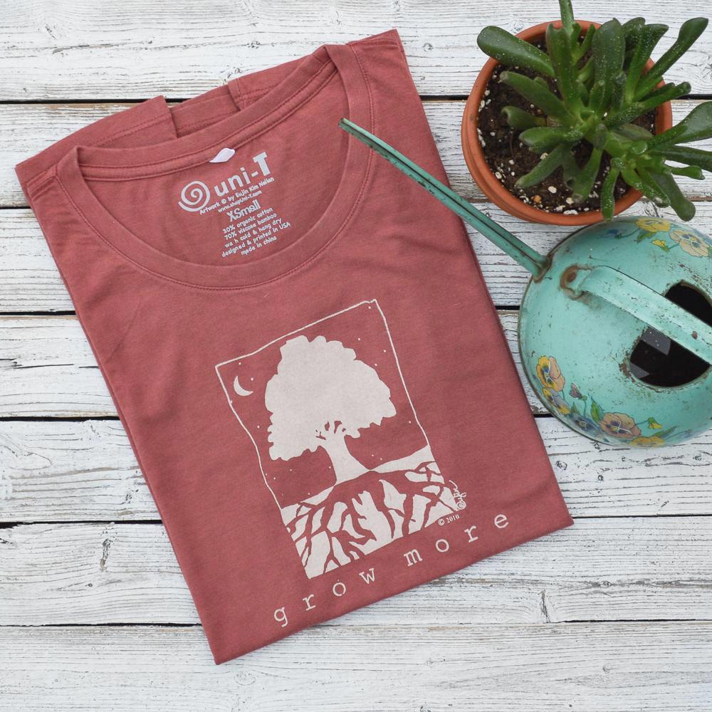 Women's Tree T-Shirt in Organic Cotton & Bamboo folded on wood with succulent and watering can, eco-friendly 'Grow More' graphic tee by Uni-T.