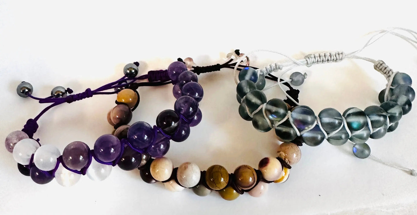 Set of woven bead bracelets with adjustable nylon cords in gemstone and glass bead styles. Features purple, brown, and clear color options.