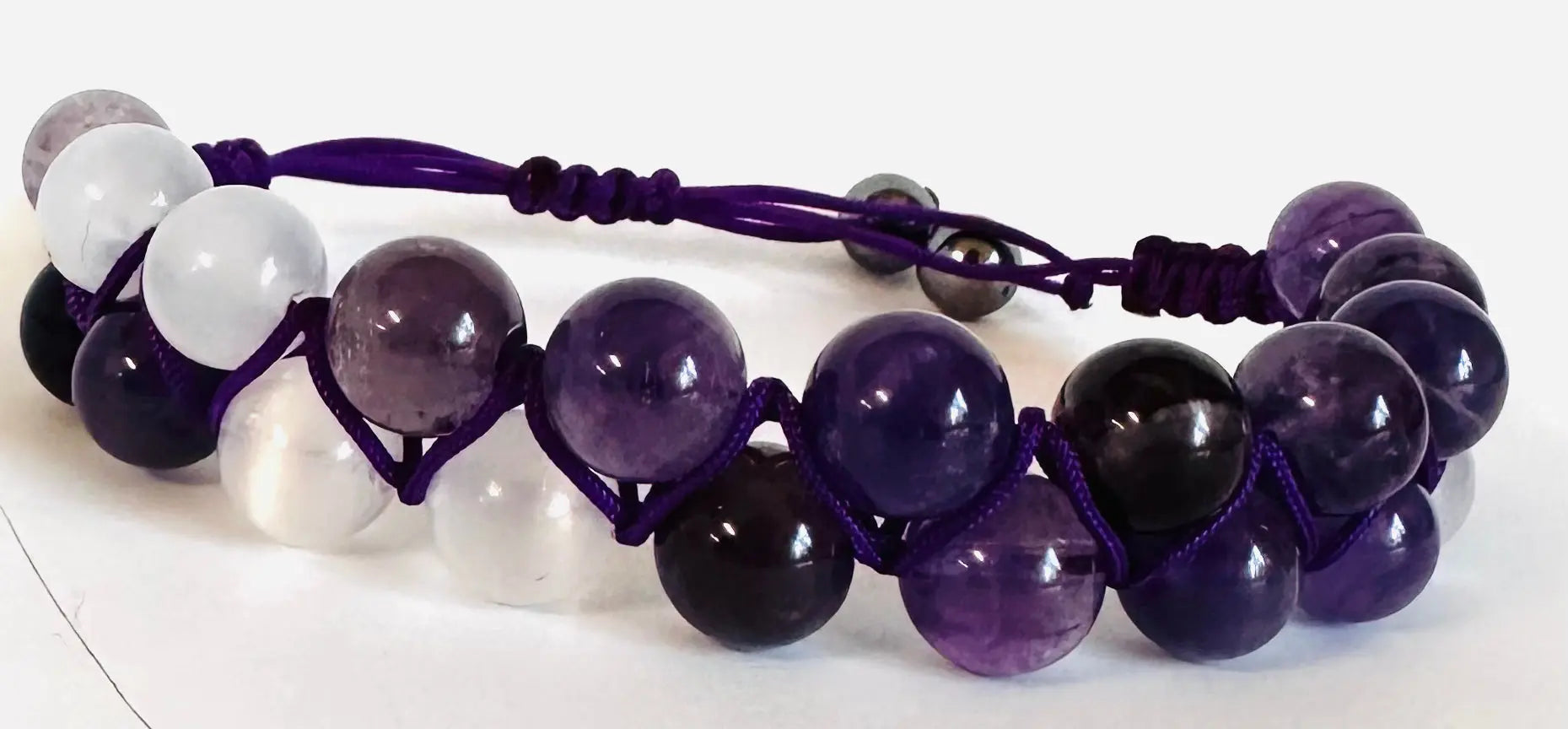 Purple and white gemstone woven bead bracelet with adjustable purple nylon cord. Ideal for fashion-forward, spiritual styles.