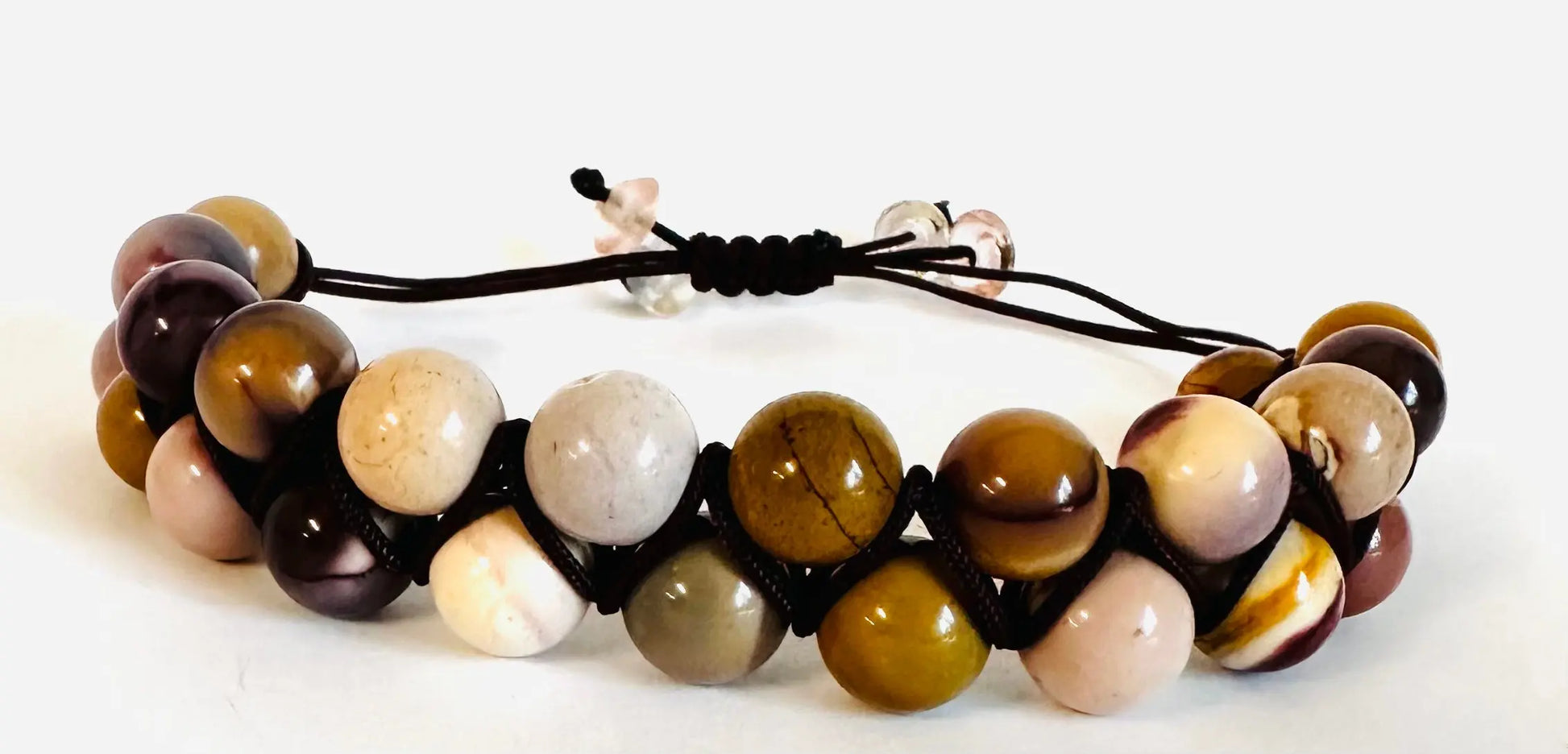 Earth-toned gemstone bead bracelet with black nylon cord in adjustable woven style. Natural and rustic accessory for casual outfits.